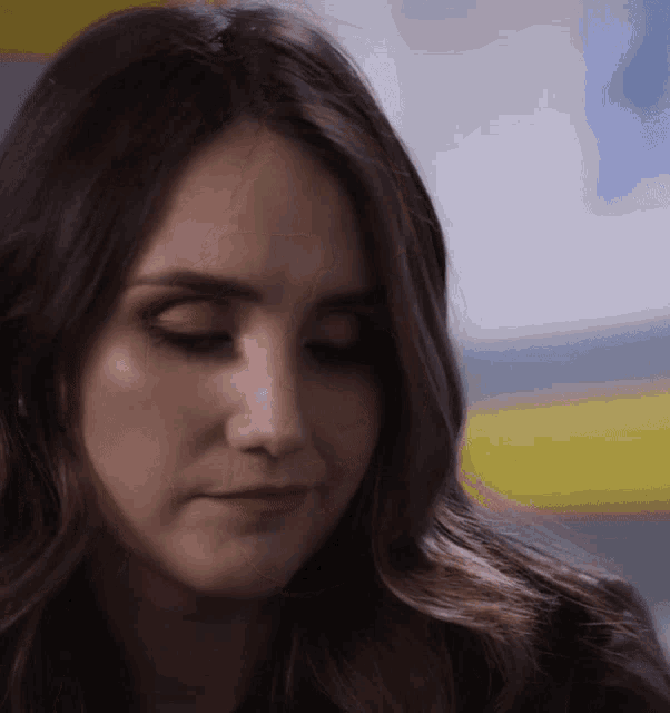 a woman with long brown hair looks down at something