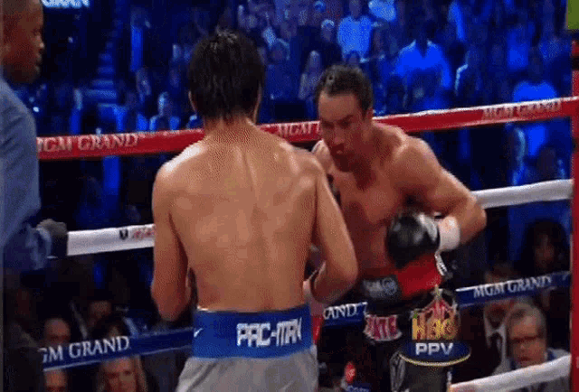 two boxers are fighting in a ring with a mgm grand banner on the ropes