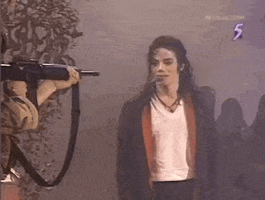 a man is holding a camera in front of a man in a black jacket .