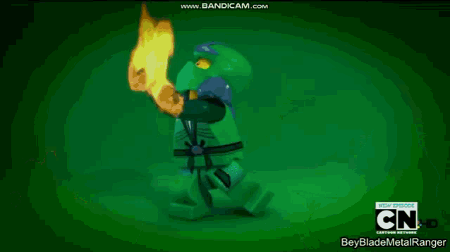 a green lego ninjago character is standing in front of a fire and a cartoon network logo .