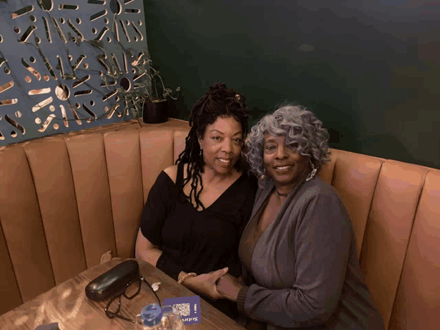 two women sit at a table in front of a sign that says ' ups '