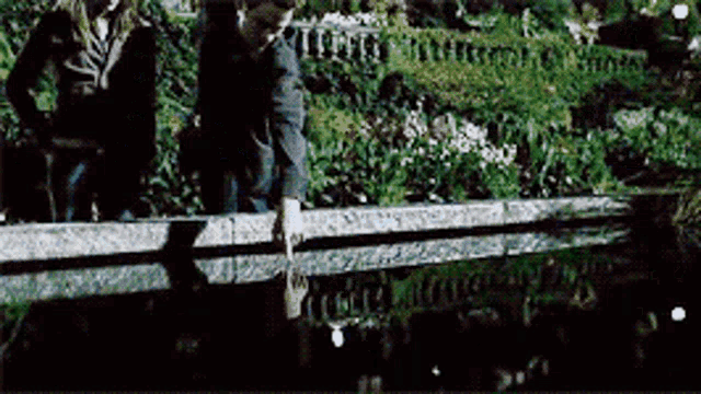 a man and woman are standing on a bridge over a river .