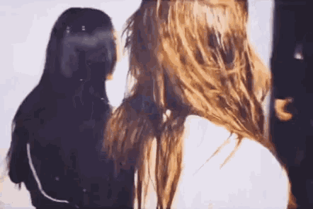 two women with long hair are standing next to each other and looking at each other .