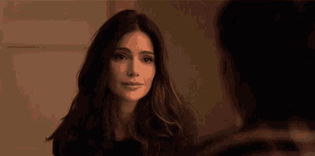 a woman with long brown hair is looking at herself in the mirror .