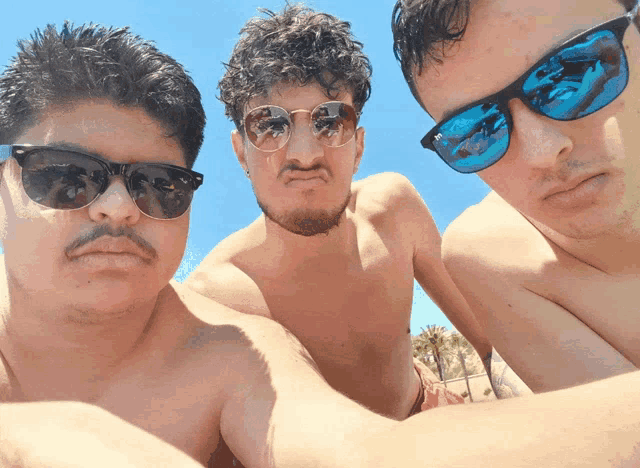 three men wearing sunglasses pose for a picture together