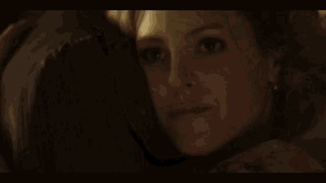 a close up of a woman 's face in a dark room with a blurred background .