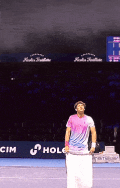 a man holding a towel on a tennis court in front of a nicolas feuillatte sign