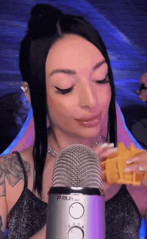 a woman eating a waffle in front of a microphone that says 09.05.24