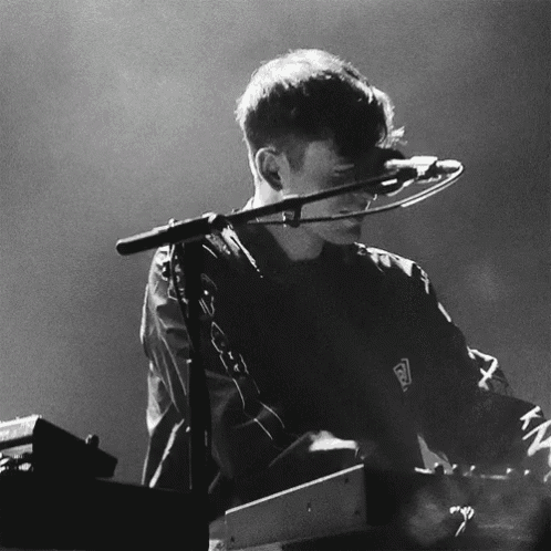 a black and white photo of a man playing a keyboard with a shirt that says reebok on it