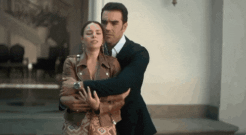 a man in a suit and tie is hugging a woman