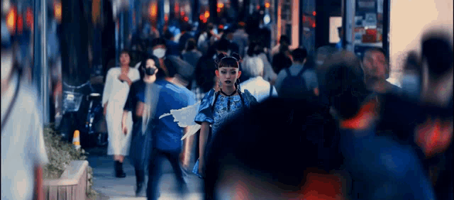 a woman in a blue dress with wings is walking through a crowd of people