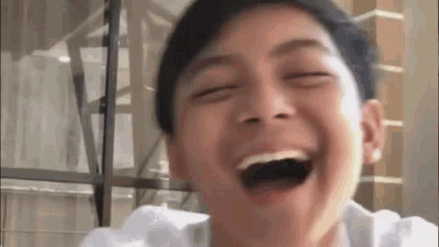 a young man is laughing with his mouth wide open .
