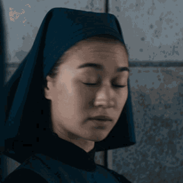 a close up of a woman wearing a blue head scarf with her eyes closed