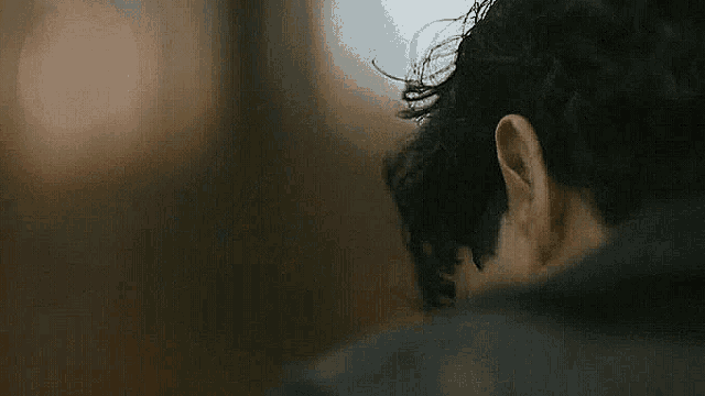 a close up of a man 's face with curly hair and a black jacket .