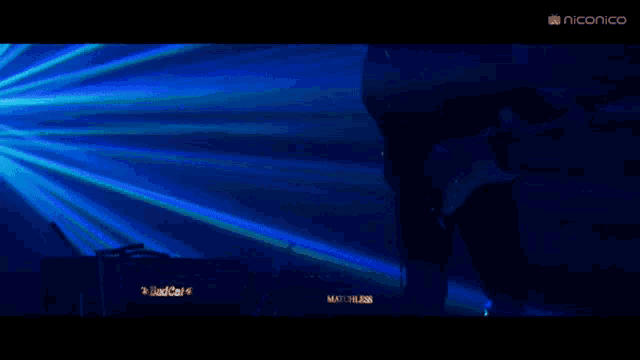 a person playing a guitar in a dark room with a niconico logo on the bottom