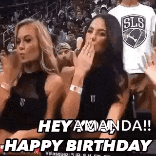 two women are sitting in the stands at a basketball game and blowing kisses .