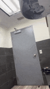 a door in a public restroom with a light switch on the wall