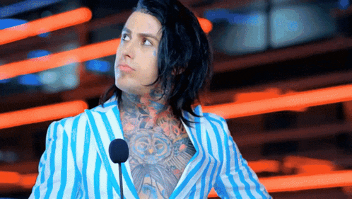 a man in a blue and white striped jacket is standing in front of a microphone