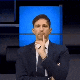 a man in a suit and tie is holding his finger to his chin
