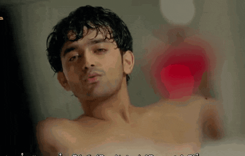 a man without a shirt is taking a bath in a bathtub .