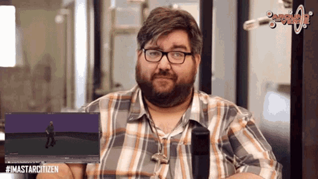 a man in a plaid shirt is holding a computer screen with #imastarcitizen written on the bottom