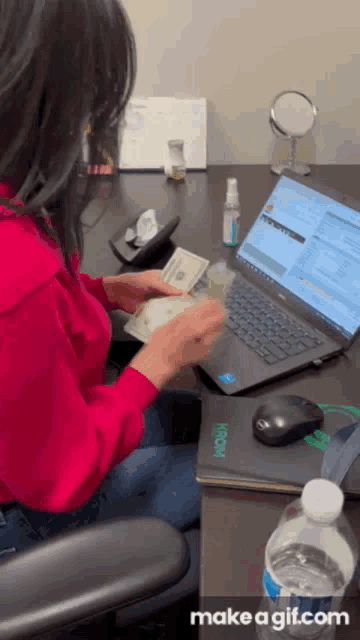 a woman is sitting at a desk with a dell laptop and a bottle of water