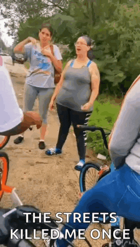 a group of people are riding bicycles down a dirt road and talking .