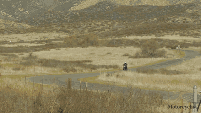 a person riding a motorcycle down a road with the word motorcyclist on the bottom right