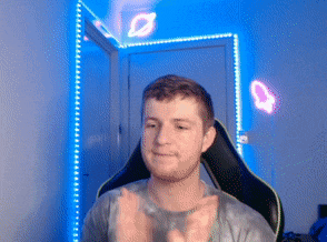 a man in a gaming chair is clapping his hands in a room with blue lights