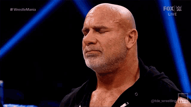 a bald man with a beard is standing in front of a fox live sign