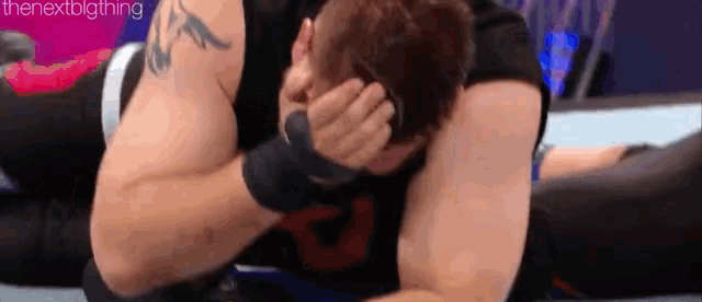 a man is covering his face with his hands while laying on the floor .