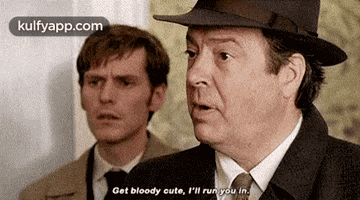 two men in suits and hats are standing next to each other and one of them is talking .
