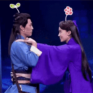 a man and a woman are standing next to each other on a stage . the woman is wearing a purple dress .