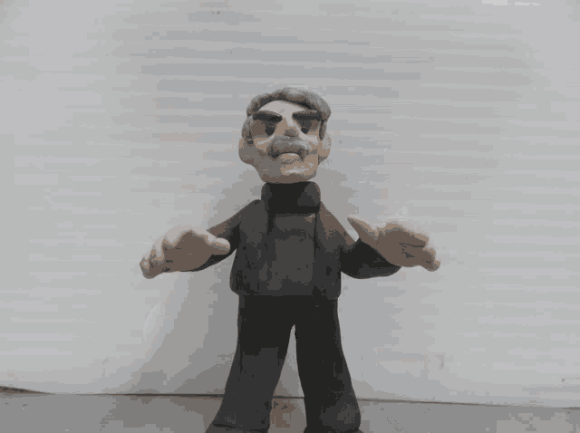 a clay figurine of a man with a mustache is pointing up