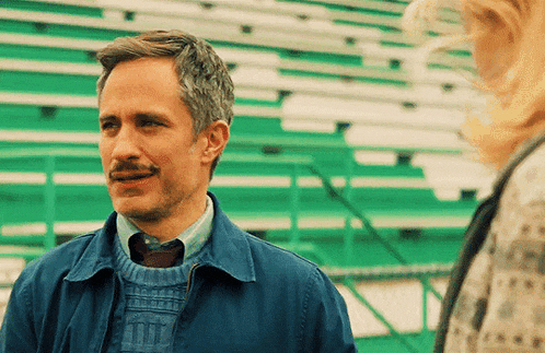 a man with a mustache is wearing a blue jacket and a sweater