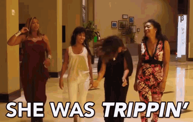 a group of women walking down a hallway with the words she was trippin '