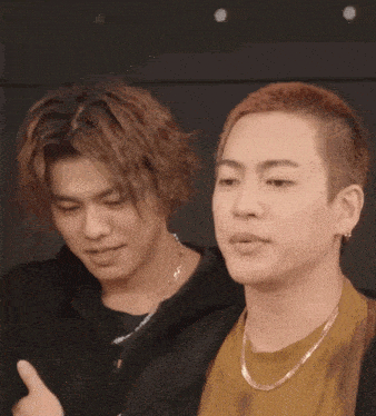 two men are standing next to each other and one is wearing a gold chain