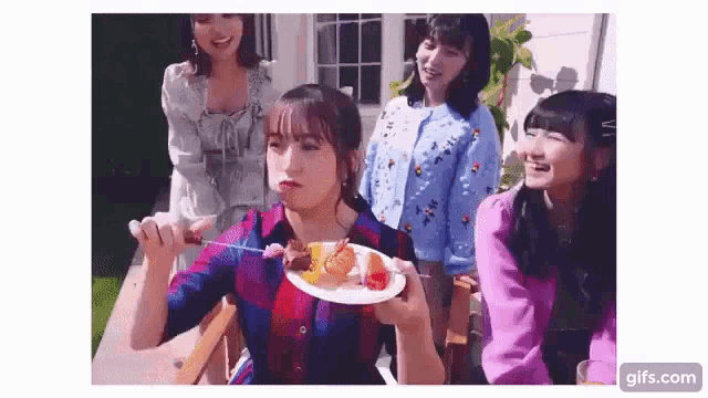 a group of young women are eating food together while sitting on a porch .
