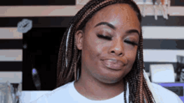 a woman with braids is smiling and making a funny face .