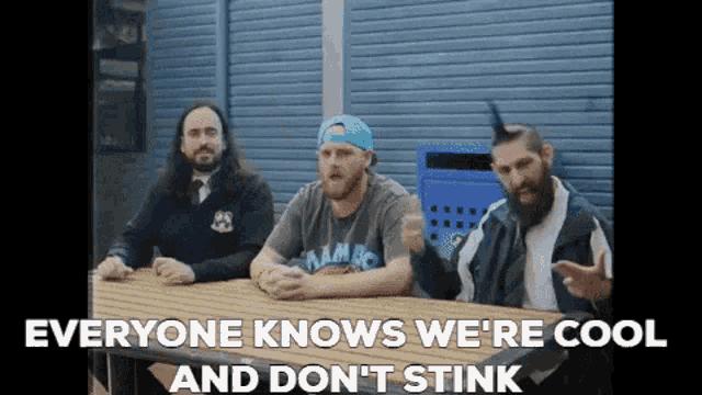 a group of men sitting at a table with the words everyone knows we 're cool and don 't stink