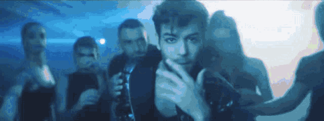 a group of people are standing around a man in a black jacket