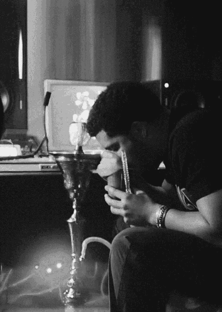 a man is smoking a hookah in front of a computer monitor