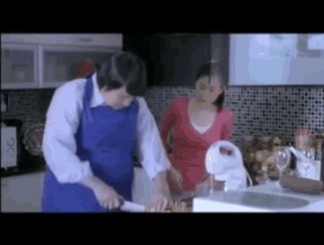 a man in a blue apron is cutting vegetables in a kitchen