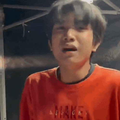 a man in a red sweater is making a funny face with his hands .