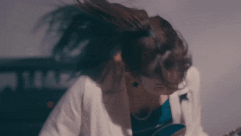 a woman with her hair blowing in the wind is sitting down