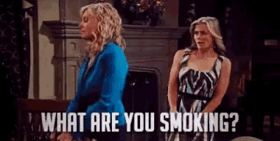 two women are standing next to each other in front of a fireplace .