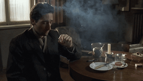 a man in a suit is smoking a cigarette