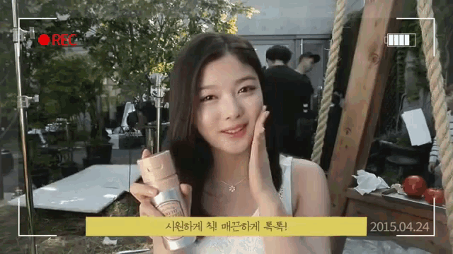 a woman is holding a bottle in front of a camera that says rec on it