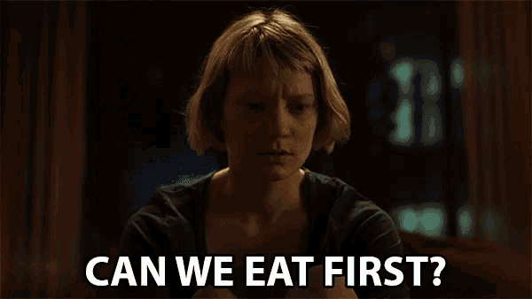 a woman sitting in a dark room with the words can we eat first