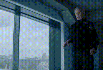 a man in a black shirt is standing in front of a window .